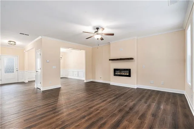a view of an empty room with wooden floor and a ceiling fan