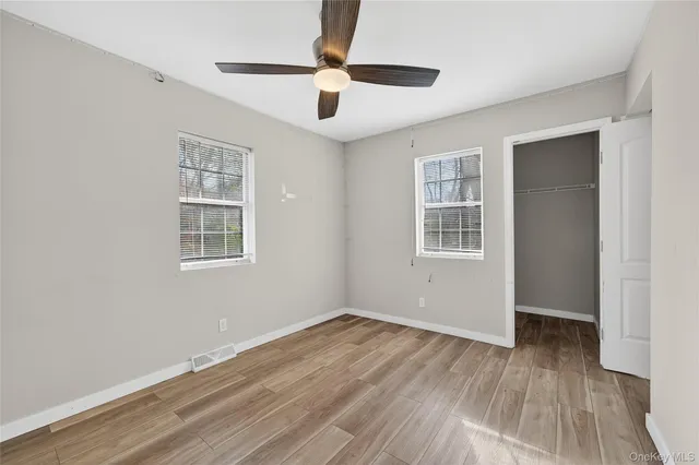 a view of empty room with wooden floor and fan