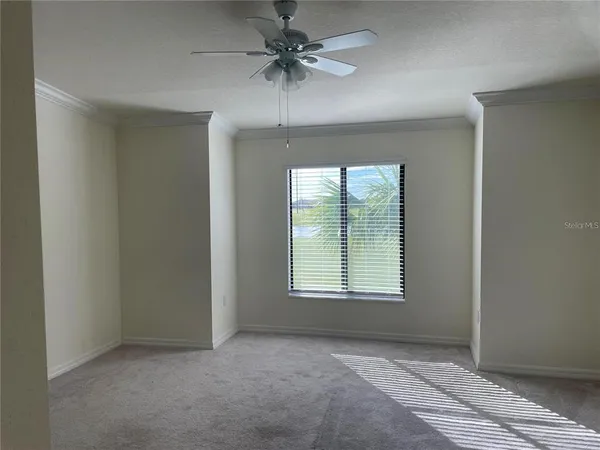 an empty room with windows and fan