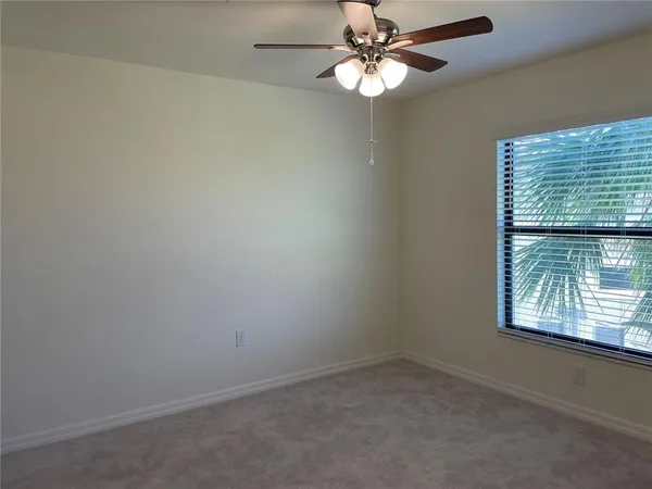 an empty room with a window and a fan