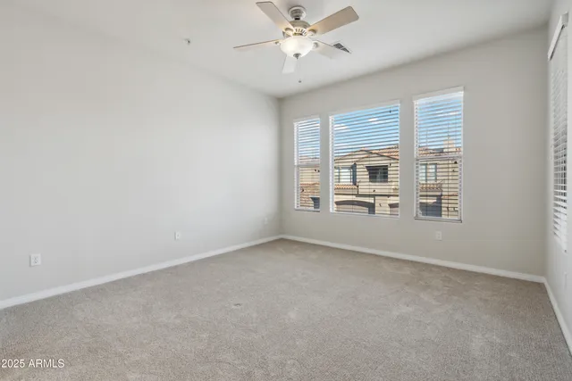 an empty room with chandelier fan and windows