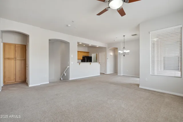 an empty room with chandelier fan and windows