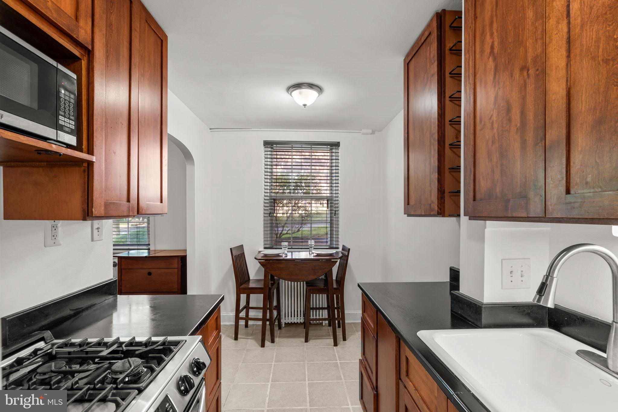 4581 MacArthur Boulevard Northwest, Unit 103 Washington, DC 20007 - Photo 11 of 28 a kitchen with granite countertop stainless steel appliances a sink stove and cabinets