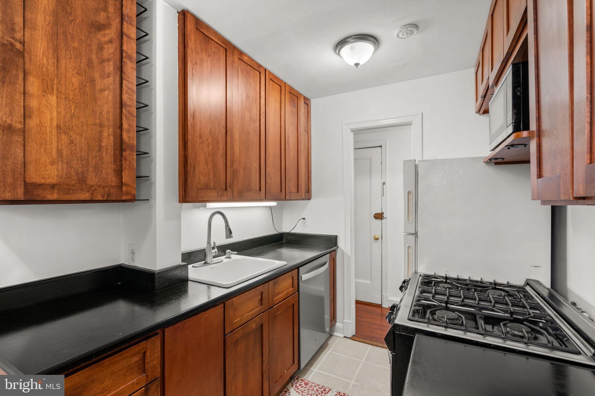 4581 MacArthur Boulevard Northwest, Unit 103 Washington, DC 20007 - Photo 9 of 28 a kitchen with stainless steel appliances granite countertop a sink stove and cabinets