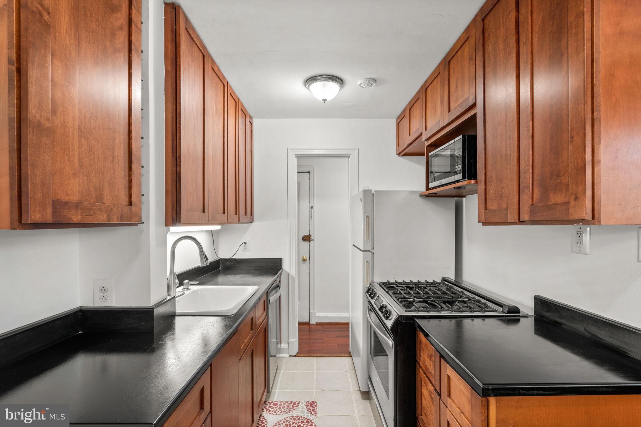 4581 MacArthur Boulevard Northwest, Unit 103 Washington, DC 20007 - Photo 10 of 28 a kitchen with granite countertop a sink a stove and cabinets