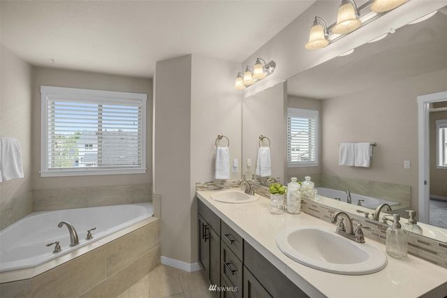 a bathroom with a bathtub a double vanity sink and a mirror