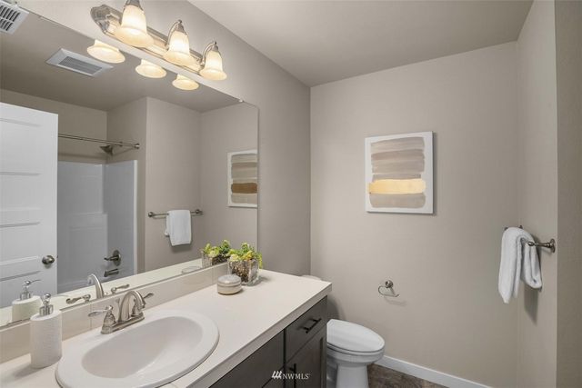 a bathroom with a granite countertop sink a toilet and a mirror