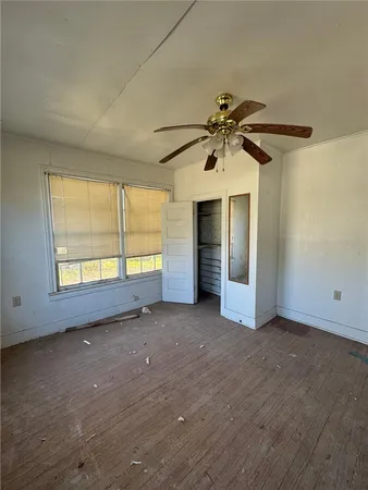 an empty room with windows and a ceiling fan