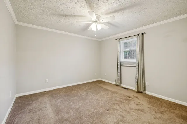 an empty room with a chandelier fan and windows