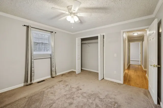 an empty room with closet and a ceiling fan