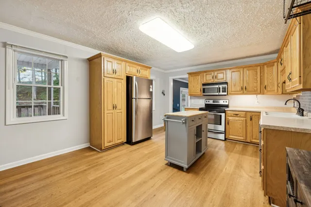 a kitchen with stainless steel appliances a stove a sink a refrigerator a window