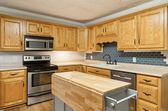 a kitchen with granite countertop wooden cabinets stainless steel appliances and a window