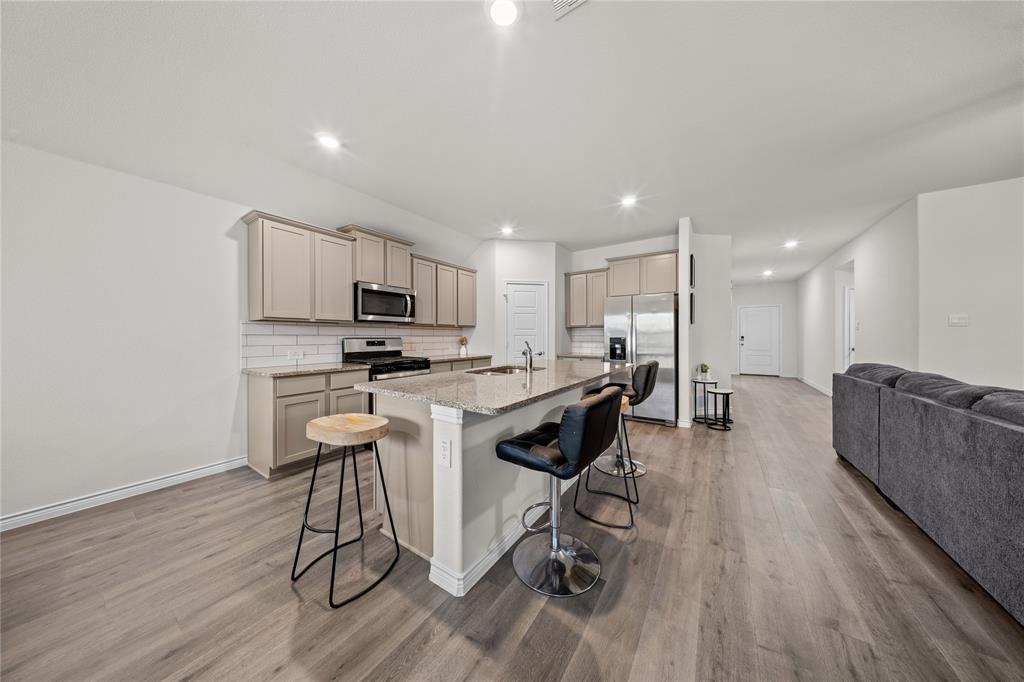 9805 Quail Pointe Road Aubrey, TX 76227 - Photo 12 of 38 Light wood-finish flooring, kitchen island with seating, stainless steel appliances, white subway tile backsplash, and recessed lighting