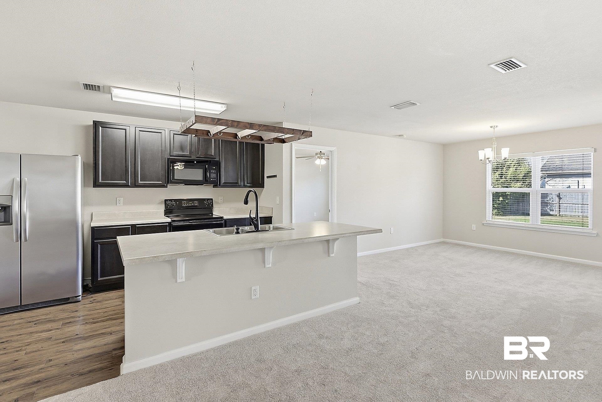 983 Summerton Drive Foley, AL 36535 - Photo 12 of 25 Kitchen featuring black appliances, a kitchen breakfast bar, light countertops, a ceiling fan, and an island with sink