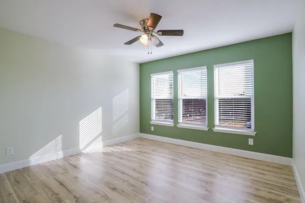 a view of an empty room with a window and wooden floor