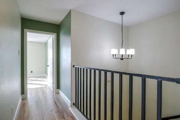 a view of a hallway with wooden floor and chandelier