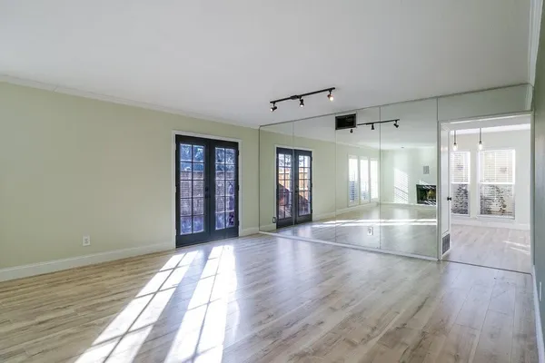 a view of an empty room with window and wooden floor