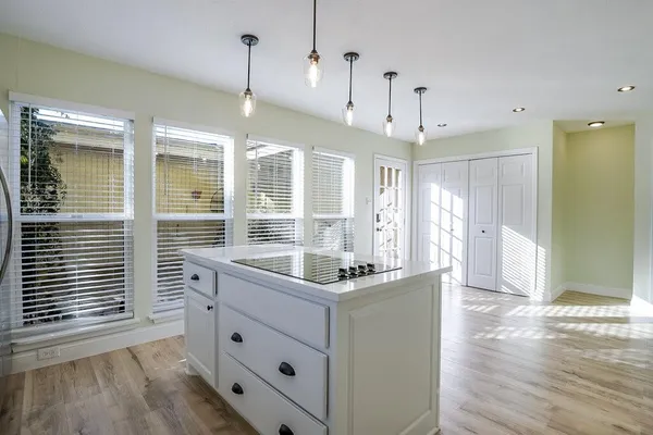 a kitchen with kitchen island granite countertop a stove a sink a refrigerator wooden floor and white cabinets