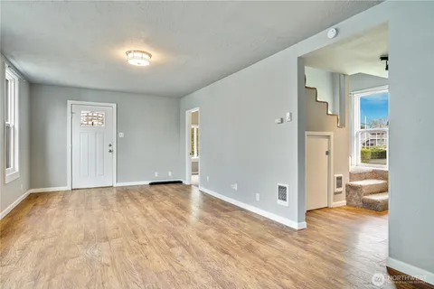 a view of a big room with wooden floor and windows