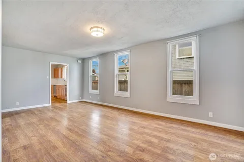 a view of an empty room with window and wooden floor
