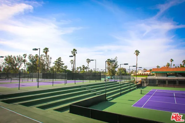a view of a tennis ground with large trees