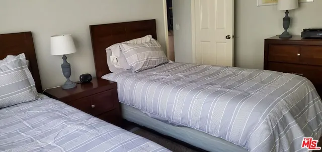 a bedroom with a bed and a lamp on dresser