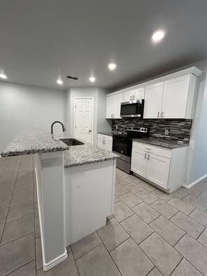 8411 10th Street Lubbock, TX 79416 - Photo 4 of 10 a kitchen with granite countertop a sink and white cabinets