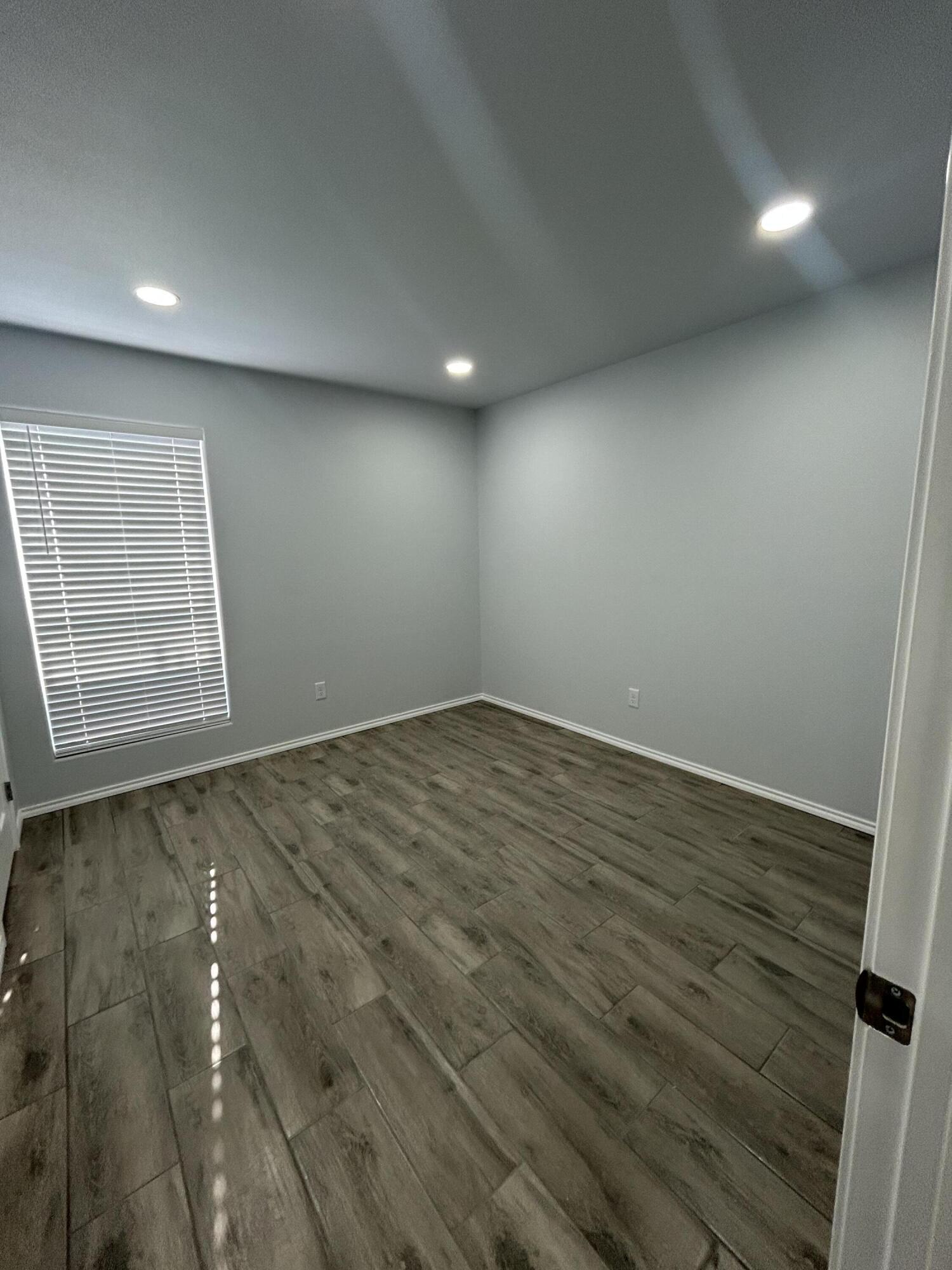 8411 10th Street Lubbock, TX 79416 - Photo 6 of 10 an empty room with wooden floor and windows