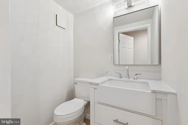 a bathroom with a toilet sink vanity and mirror