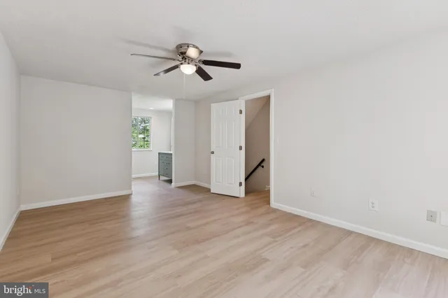 an empty room with wooden floor chandelier fan and windows