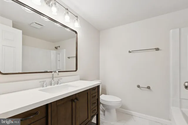 a bathroom with a sink a toilet a mirror and shower