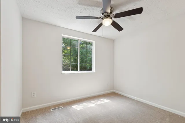 an empty room with a window and a fan