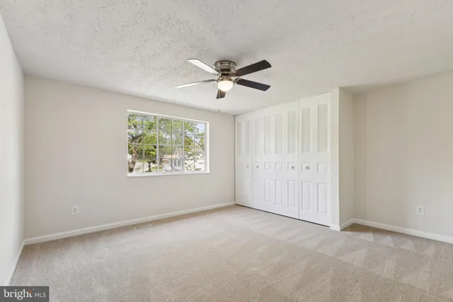 an empty room with windows and fan