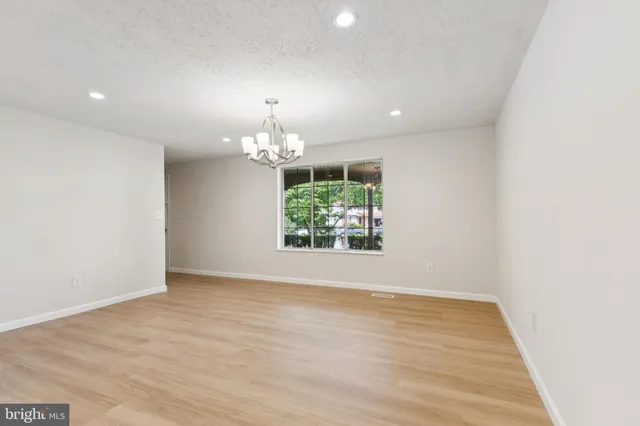 an empty room with wooden floor chandelier and window