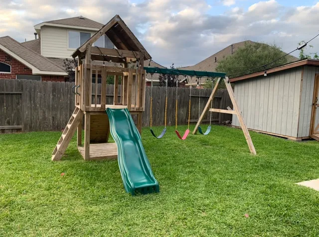 a view of a backyard with a slide and swing