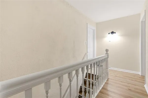 a view of a hallway with wooden floor and a bathroom