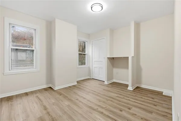 an empty room with wooden floor and windows