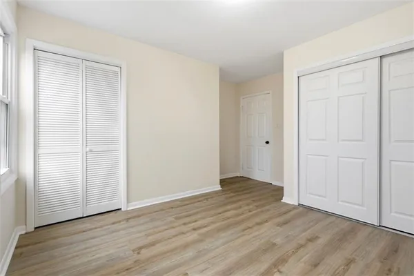 an empty room with wooden floor & closet area