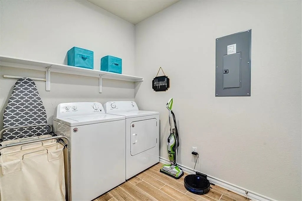 317 Capstone Road Liberty Hill, TX 78642 - Photo 9 of 10 Laundry room with electric panel, wood tiled floors, and washer and clothes dryer