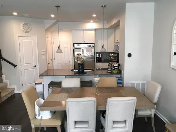 a kitchen with stainless steel appliances kitchen island granite countertop a dining table chairs and a refrigerator