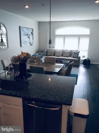 a living room with large couches and kitchen view with wooden floor
