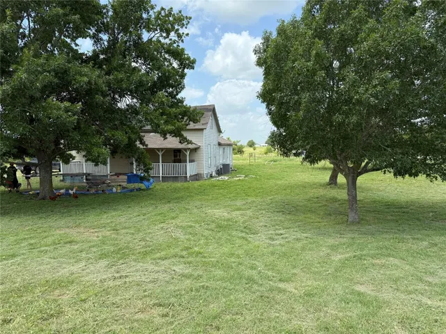 a view of a house with a big yard and large trees