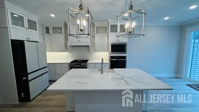 a kitchen with stainless steel appliances kitchen island granite countertop a refrigerator a stove and a sink with wooden floor