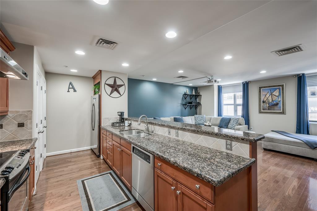 a large kitchen with kitchen island a large counter top and stainless steel appliances