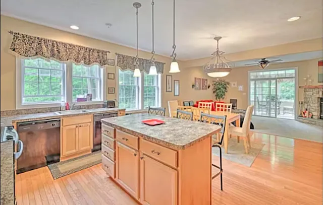 a open kitchen with stainless steel appliances granite countertop a stove and kitchen island with a large window