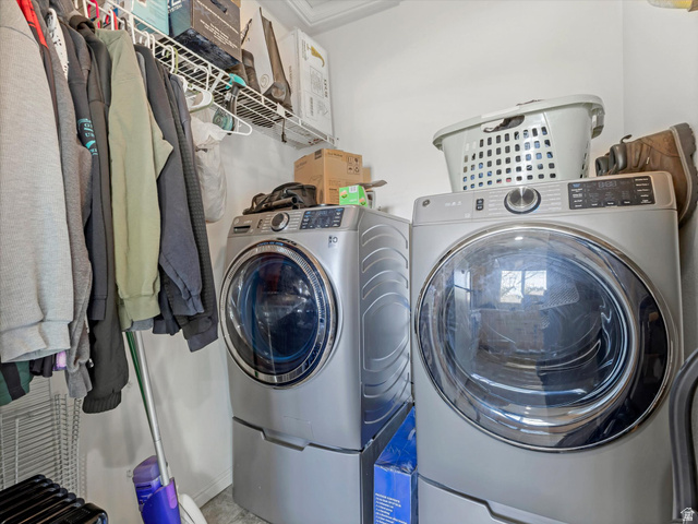5038 West Red Shale Road Herriman, UT 84096 - Photo 7 of 16 Dedicated laundry area featuring front-loading appliances, white wire shelving, and neutral wall tones