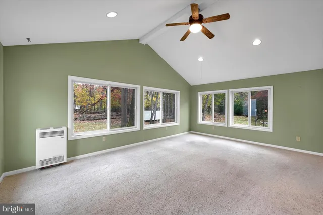 a view of an empty room with a window and kitchen view