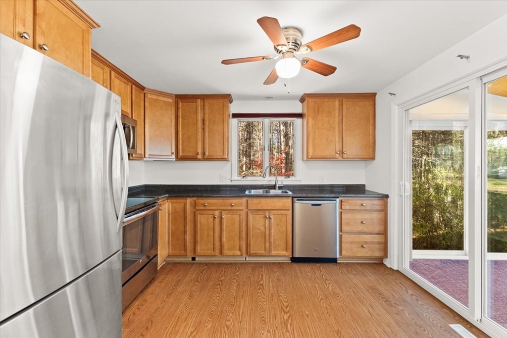 139 Burt Street, Unit 6 Norton, MA 02766 - Photo 14 of 31 a kitchen with stainless steel appliances granite countertop a refrigerator a sink dishwasher a stove and a dining table with wooden floor