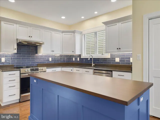 a kitchen with kitchen island granite countertop a sink stove and cabinets