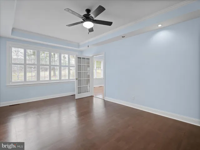 an empty room with wooden floor fan and windows